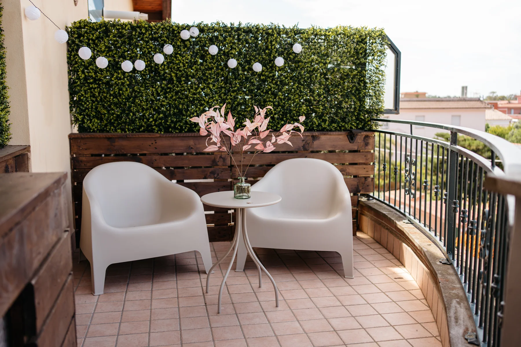 Albero: balcony with two white armchairs, a small table and green screening